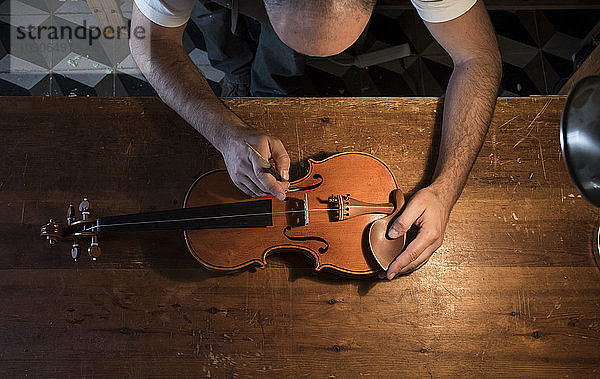 Luthier adjusting the sound post of a violin in his workshop