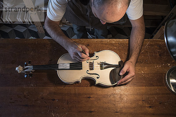 Luthier adjusting the sound post of an unvarnished violin in his workshop
