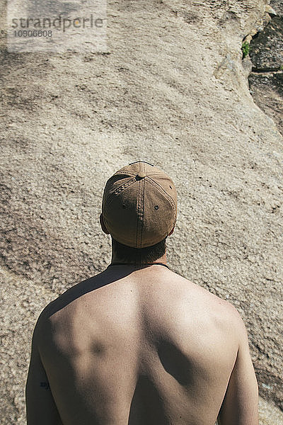 Back of a shirtless man with a gap looking at a wall before climbing