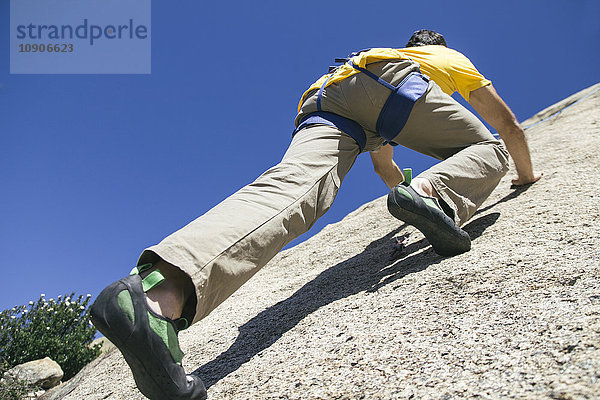 Mann klettert in einer Granitwand