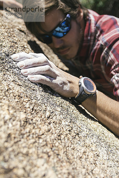 Hand of a climber with sunglasses with powder chalk magnesium during a climbing