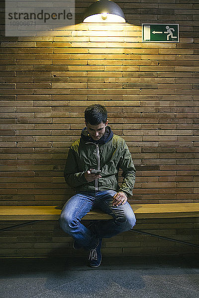 Man sitting on a bench looking at his smartphone