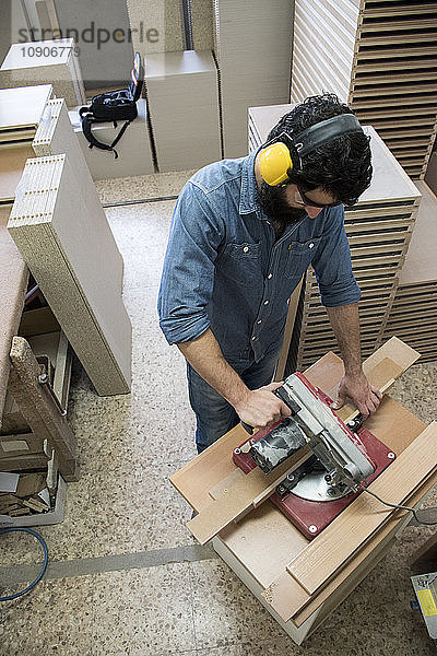 Carpenter with hearing protection and safety glasses using a circular saw