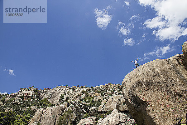 Climber on the top of a rock with outstretched arms