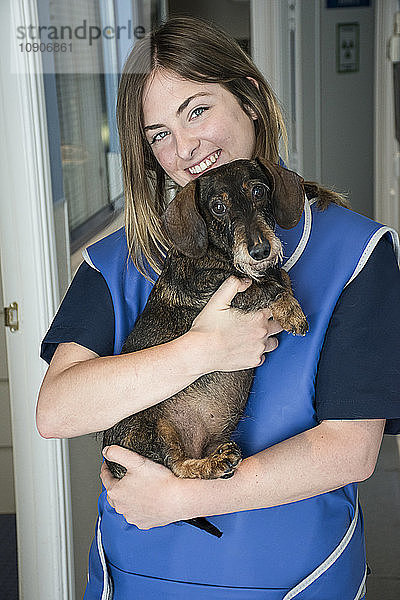 Portrait of smiling veterinarian holding dog in her arms