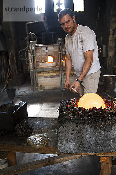Man putting molten glass in a mold in a glass factory