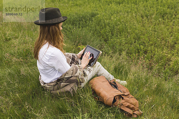 Frau sitzend auf einer Wiese mit digitalem Tablett