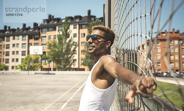 Junger Mann mit Sonnenbrille auf dem Basketballfeld