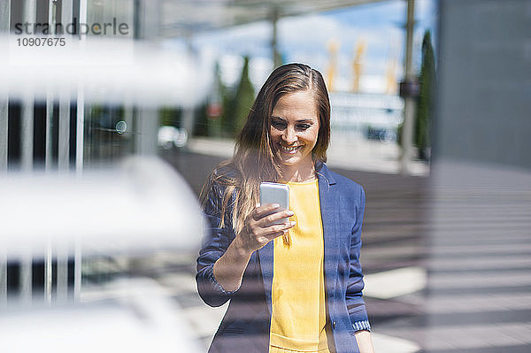 Smiling woman outdoors looking at cell phone