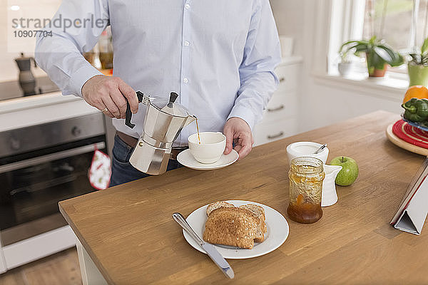 Man pouring espresso into cup in his kitchen  partial view