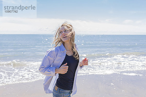 Portrait of smiling young woman running at seaside