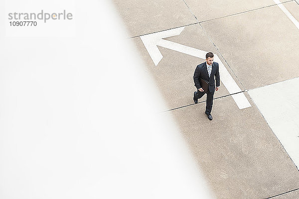 Businessman walking on paving with large arrow