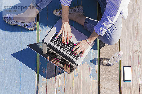 Woman using laptop on wooden boardwalk