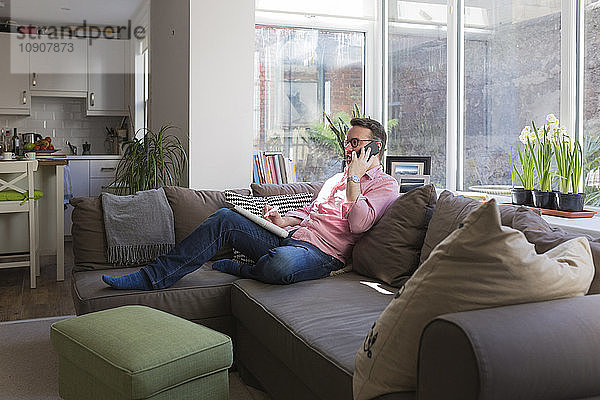 Mature man sitting on couch talking on the phone