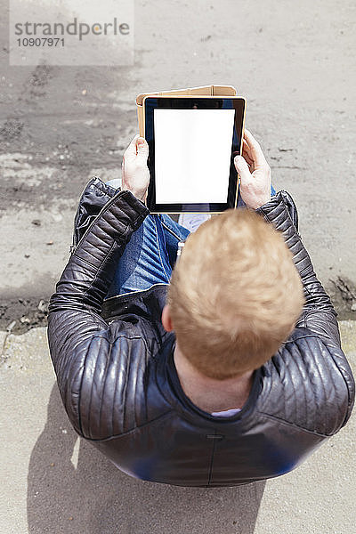 Back view of young man looking at digital tablet  seen from above