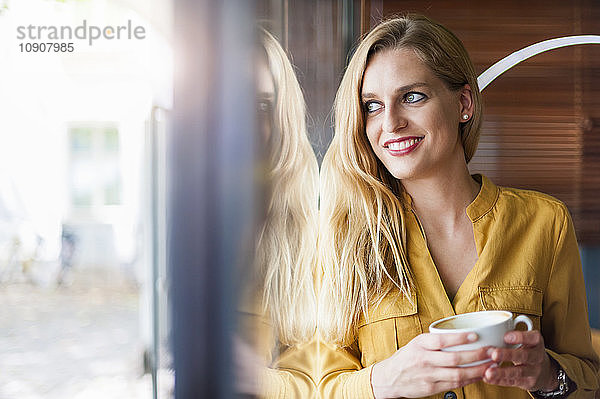 Portrait of smiling woman in a coffee shop looking through window