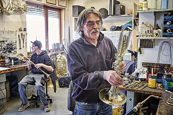 Instrument maker examining trumpet in workshop