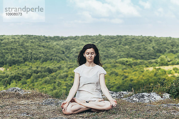 Young woman meditating on the cliff