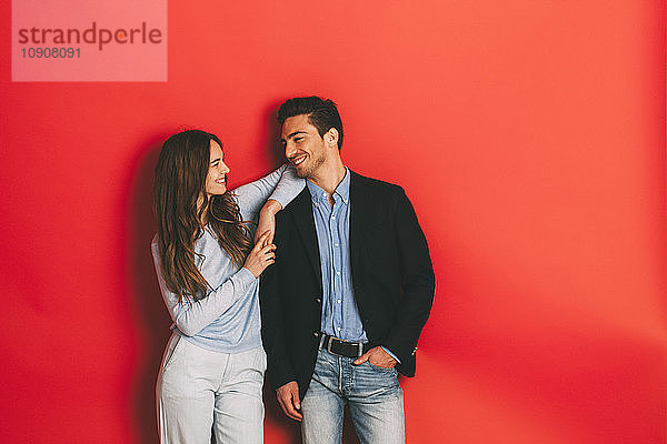 Portrait of happy young couple in front of red background