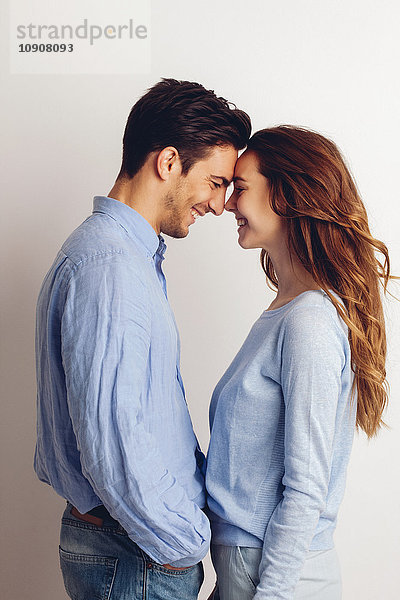 Fröhliches junges Paar vor weißem Hintergrund stehend
