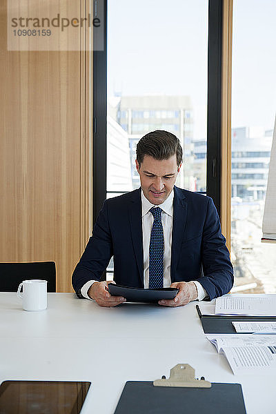 Portrait of businessman at office desk looking at folder