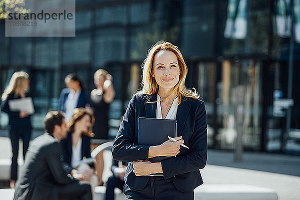 Portrait of smiling businesswoman outside office building