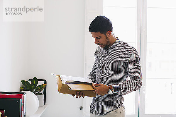 Young man in office reading files