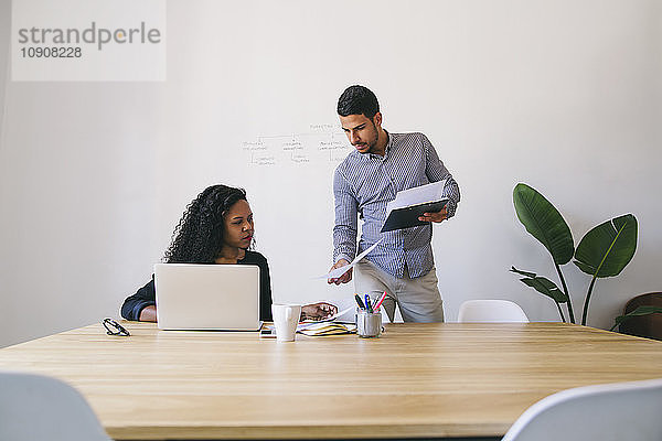 Young businessman and woman working together in office  using laptop