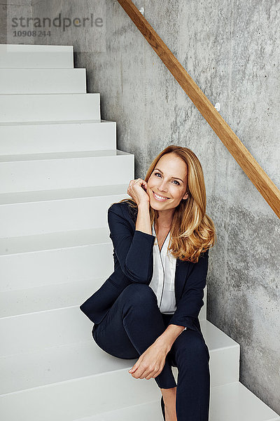 Porträt einer lächelnden Geschäftsfrau auf der Treppe sitzend