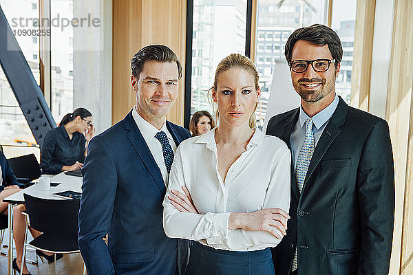 Confident businesspeople in office with meeting in background