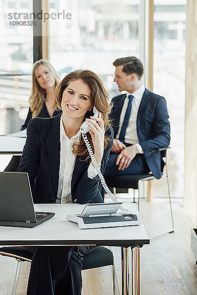 Smiling businesswoman at office desk on the phone