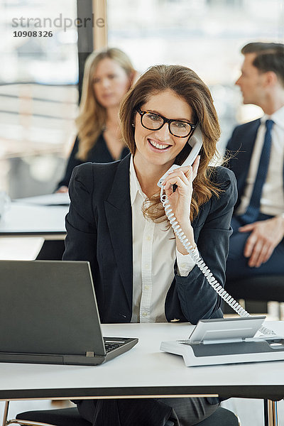 Lächelnde Geschäftsfrau am Schreibtisch am Telefon