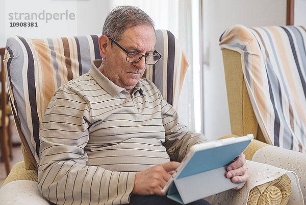 Senior Mann zu Hause mit digitalem Tablett