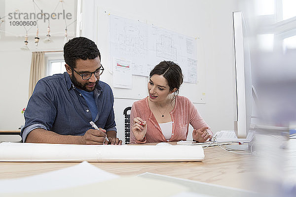 Man and woman discussing at desk in office