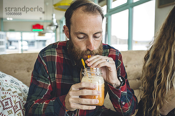 Bearded man drinking organic juice in cafe