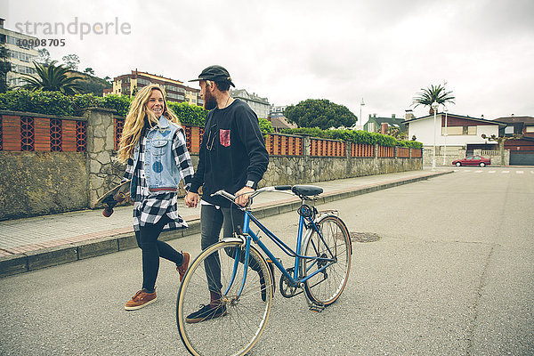 Paar mit Fahrrad und Skateboard zu Fuß auf der Straße