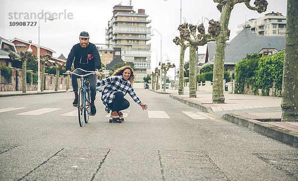 Glückliches Paar mit Fahrrad und Skateboard auf der Straße