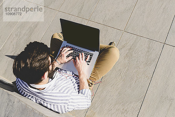 Young man sitting on the ground using laptop