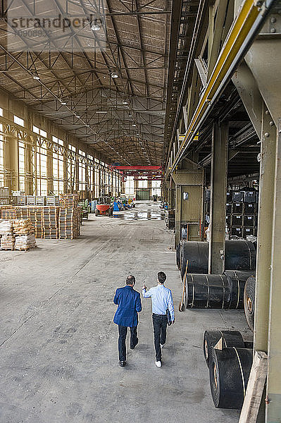 Two men walking through factory hall