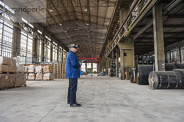 Manager standing in factory hall looking through VR glasses