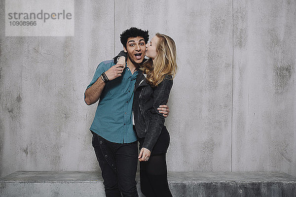 Couple in front of concrete wall  kissing