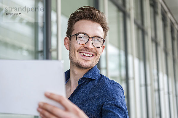 Porträt eines lächelnden jungen Geschäftsmannes mit digitalem Tablett
