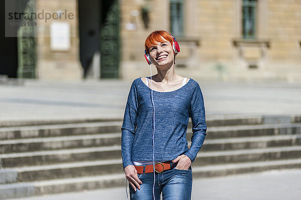 Lächelnde junge Frau beim Musikhören im Freien