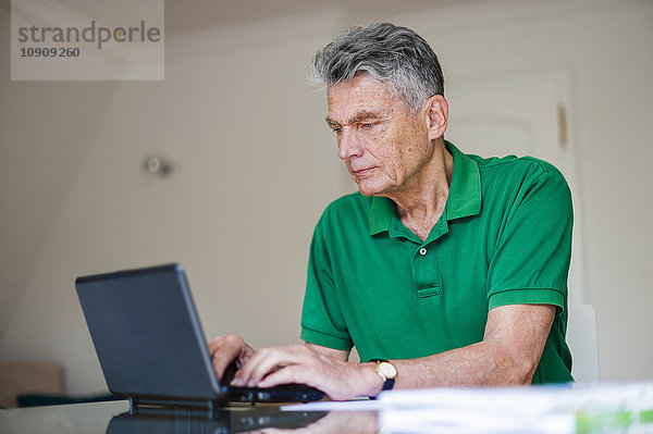 Senior Mann am Schreibtisch sitzend mit Laptop