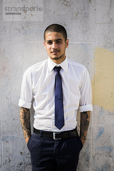 Porträt eines jungen Geschäftsmannes mit Tattoos auf den Unterarmen