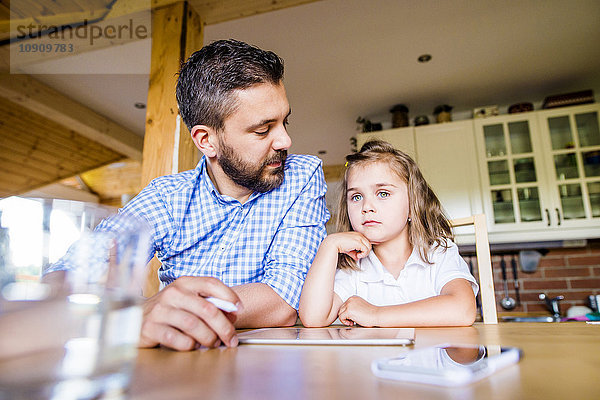 Vater und Tochter sitzen zu Hause mit digitalem Tablett