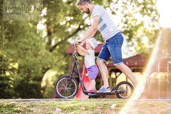 Vater und kleine Tochter zusammen auf einem Roller