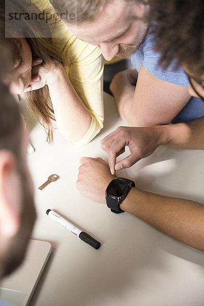 Kreative Profis im Büro mit Blick auf smartwatch
