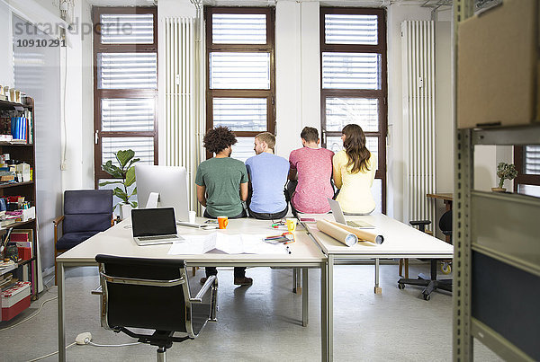 Team von Kreativprofis sitzt auf dem Schreibtisch im Büro