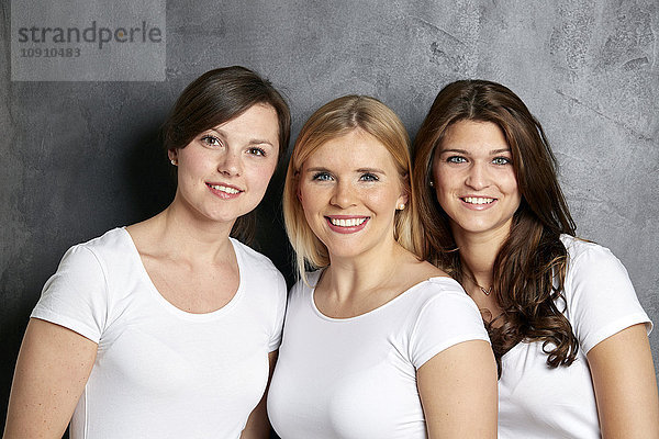 Gruppenbild von drei lächelnden Freunden